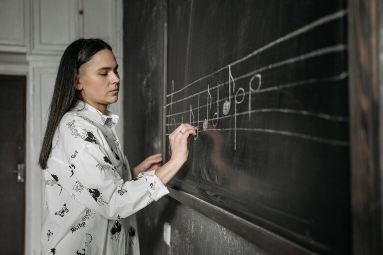 A woman drawing musical notes on a chalkboard in a classroom setting.