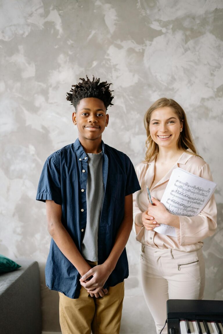 African American student and teacher in a music lesson holding sheets with a piano.