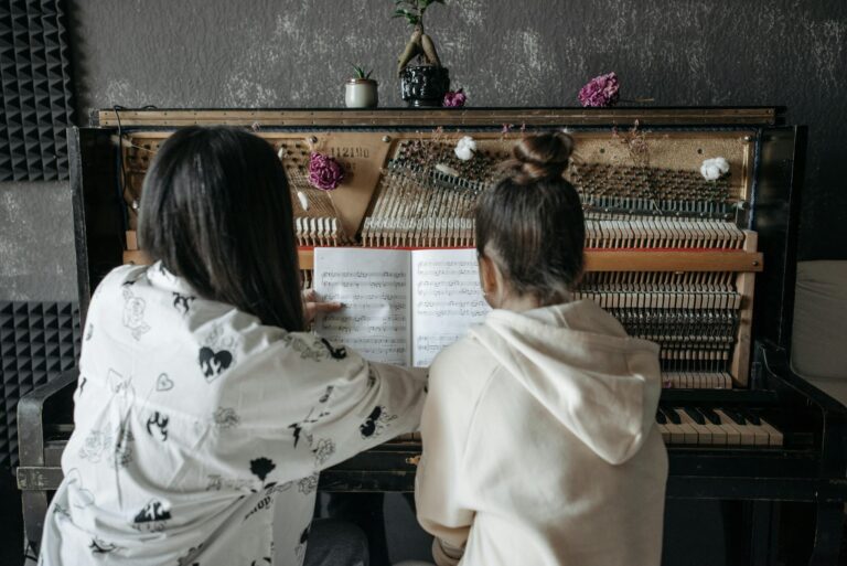 Back view of a piano lesson featuring a teacher guiding a student on music notation.
